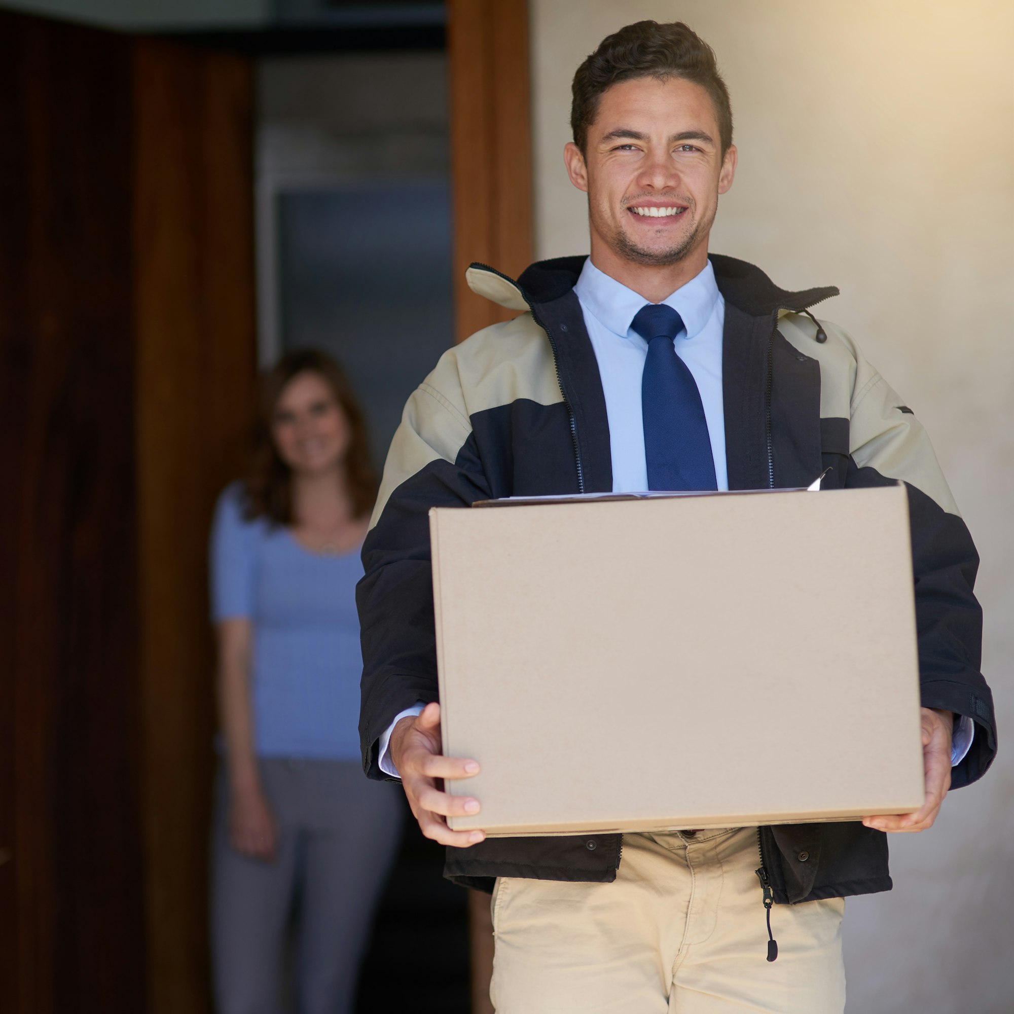 Shot of a handsome young delivery man making a delivery to a customer at her home